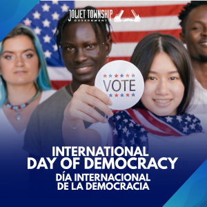 Four smiling people are standing in front of the American flag. One woman holds a button that says "Vote"